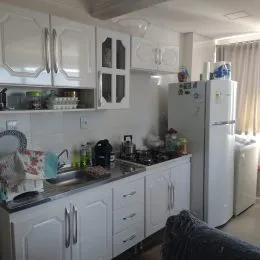 Foto de uma cozinha com armários brancos e eletrodomésticos.