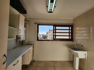 Interior de uma cozinha ou área de serviço com pia e revestimento de cerâmica.