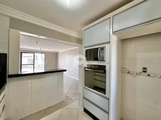 Interior de uma cozinha com armários brancos e piso de cerâmica.