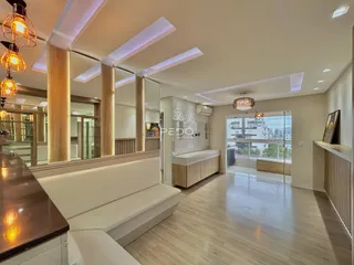 Sala de estar moderna com piso de madeira clara e grandes janelas de vidro.