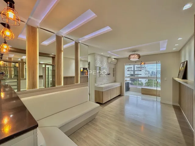 Sala de estar moderna com piso de madeira clara e grandes janelas de vidro.