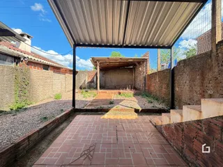 Vista de um pátio externo com piso de tijolos e paredes de alvenaria.