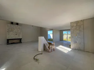Espaço interno amplo com lareira e materiais de construção no centro da sala.