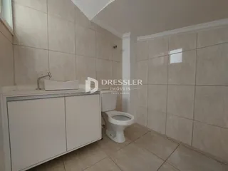 Banheiro com revestimento cerâmico claro e piso de tonalidade neutra.