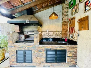 Área gourmet externa com churrasqueira e pia de cozinha em tijolo.
