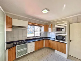 Foto da cozinha com armários de madeira e bancada escura.