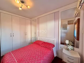 Quarto com armários embutidos e cama vermelha em um imóvel.