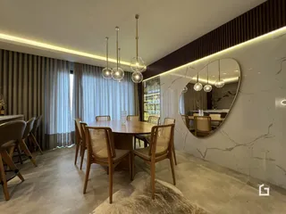Sala de jantar com mesa de madeira e grandes janelas.