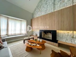 Sala de estar com lareira e painel de madeira em um imóvel no Brasil.
