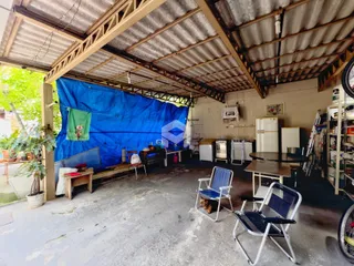Vista de uma área externa coberta com estrutura de telhado de zinco e um tecido azul.