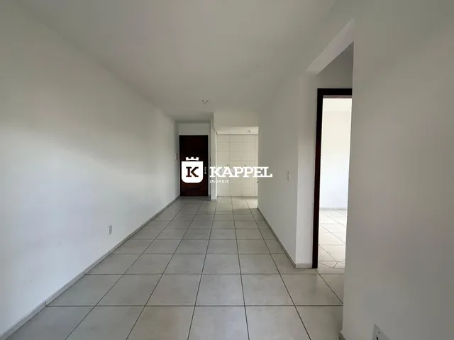 Corredor interno com paredes brancas e piso de cerâmica claro.