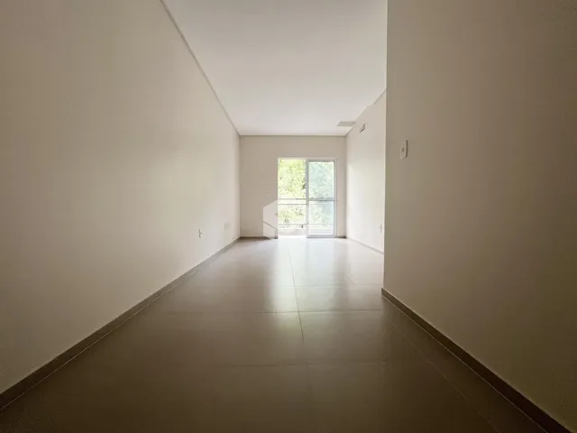 Corredor interno de uma residência com paredes brancas e piso claro.