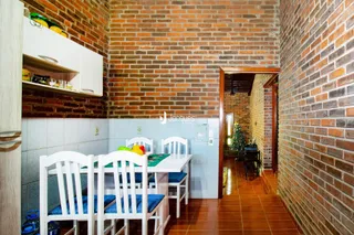 Imagem de um ambiente interno com paredes de tijolo aparente e uma mesa de jantar branca.