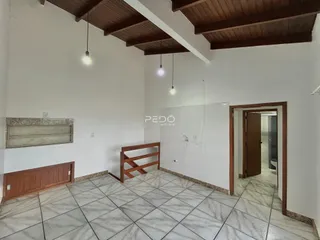 Interior de uma sala com piso de cerâmica e teto de madeira.