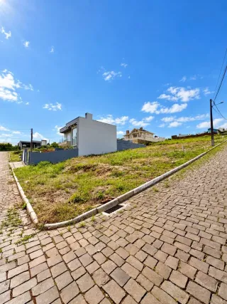 Fachada de uma casa branca em Lajeado, Brasil, com gramado e calçada no primeiro plano.