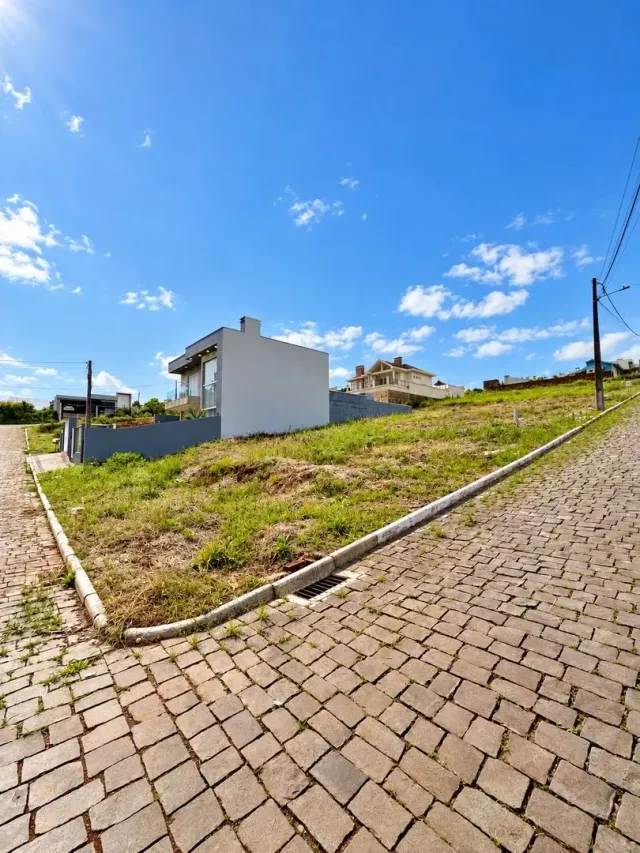 Fachada de uma casa branca em Lajeado, Brasil, com gramado e calçada no primeiro plano.