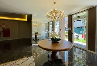 Sala de estar com piso de mármore escuro e lustre dourado.