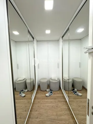 Hall de entrada com paredes espelhadas e piso de madeira clara.