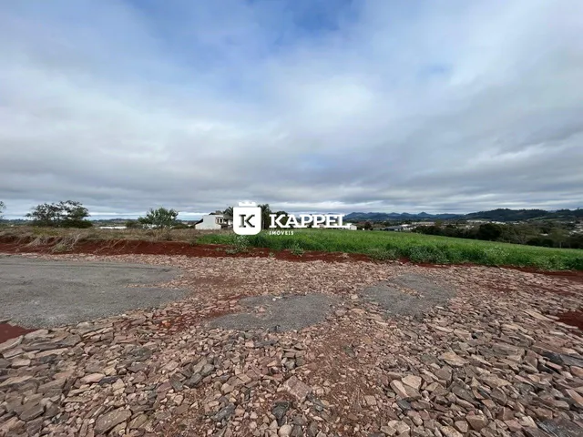Vista externa de uma propriedade com um campo gramado e uma placa ao fundo.