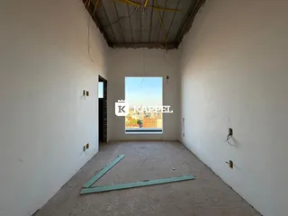 Hall de uma sala com paredes brancas e um vão para a vista externa.