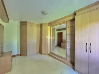 Quarto com armários em madeira clara e piso de cerâmica.