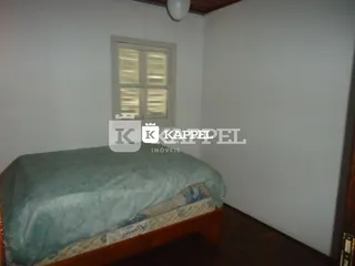 Quarto com cama de madeira e paredes brancas.