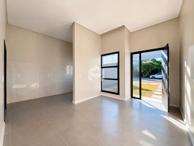 Ambiente interno de uma sala com piso de cerâmica e porta de vidro para o exterior.