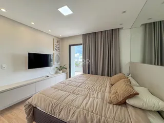 Quarto moderno com cama grande e televisão montada na parede.
