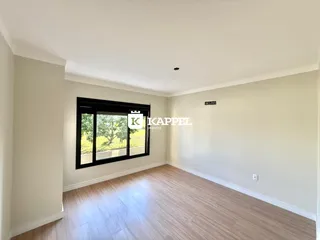 Uma sala de estar com piso de madeira e uma grande janela com vista para a natureza.