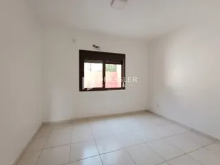 Ambiente interno de uma sala com piso de cerâmica e janela.