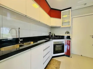 Cozinha moderna com armários brancos e bancadas pretas.