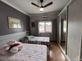 Quarto com cama e janela em um apartamento com piso de madeira.