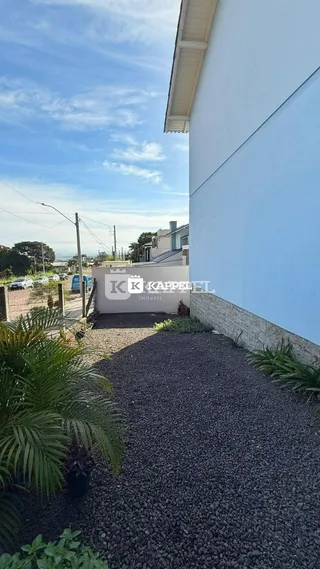 Fachada branca de uma residência com vegetação no primeiro plano.