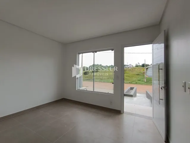 Ambiente interno de uma sala com piso de cerâmica e vista para o exterior.