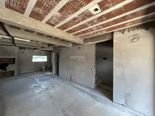 Interior de um espaço com teto de madeira exposta e paredes de concreto.