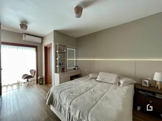Quarto com cama e piso de madeira clara.