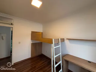 Interior de um cômodo com piso de madeira e paredes brancas.