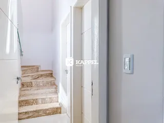 Vista de um corredor com escadaria de mármore claro e portas brancas.