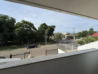 Vista externa de uma propriedade com árvores e uma rua no fundo.