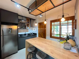 Interior de uma cozinha moderna com armários escuros e iluminação pendente.