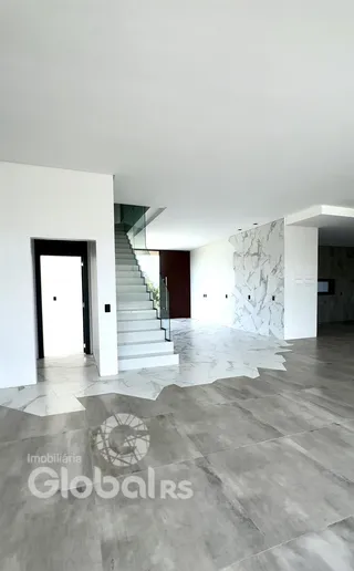 Interior de um espaço com escadaria e piso de pedra clara.