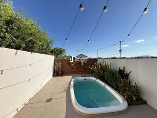 Piscina externa com paisagismo e muro branco no quintal.