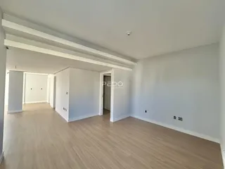 Interior de uma sala ampla com piso de madeira clara.