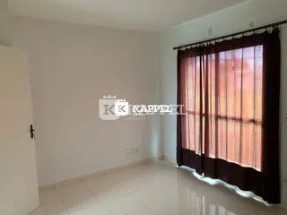 Uma sala de estar com paredes brancas e uma grande janela coberta por cortinas escuras.