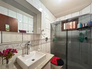 Foto de um banheiro com azulejos brancos e box de vidro.