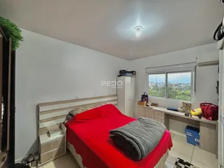 Quarto com cama vermelha e janela de vista para a paisagem.