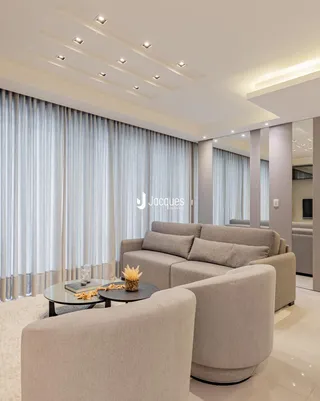 Sala de estar moderna com sofá grande e cortinas claras.