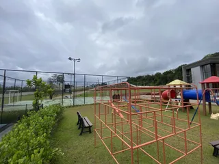 Foto de uma área externa com equipamentos de playground e gramado verde.
