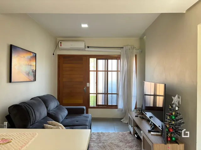 Sala de estar com sofá e vista para o exterior da casa.