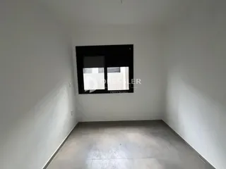 Vista interna de um ambiente com paredes brancas e piso claro.